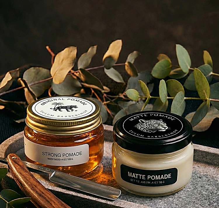 Pomadas Strong y Matte de Tulum Barbershop junto a una navaja sobre piedra y eucalipto
